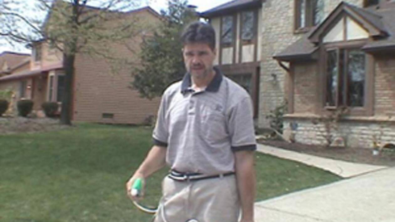 Person standing on a well-maintained lawn in front of a house.