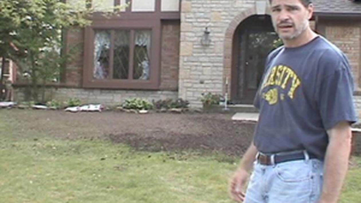 Person standing on a well-maintained lawn in front of a house.