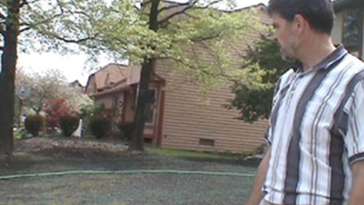 A man standing looking at a lawn covered in dirt