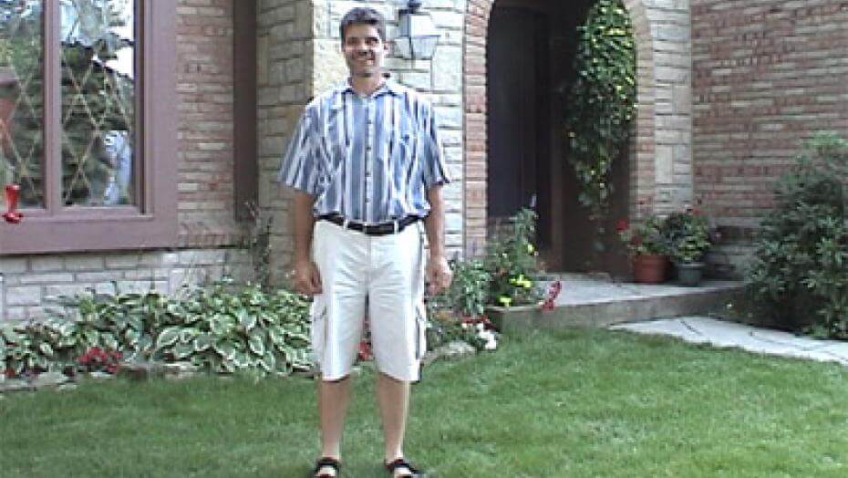 Person standing on a well-maintained lawn in front of a house.