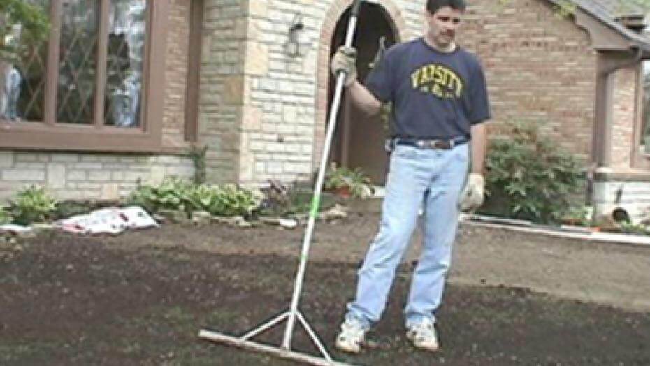 Person standing on a patch of dirt in front of a house.