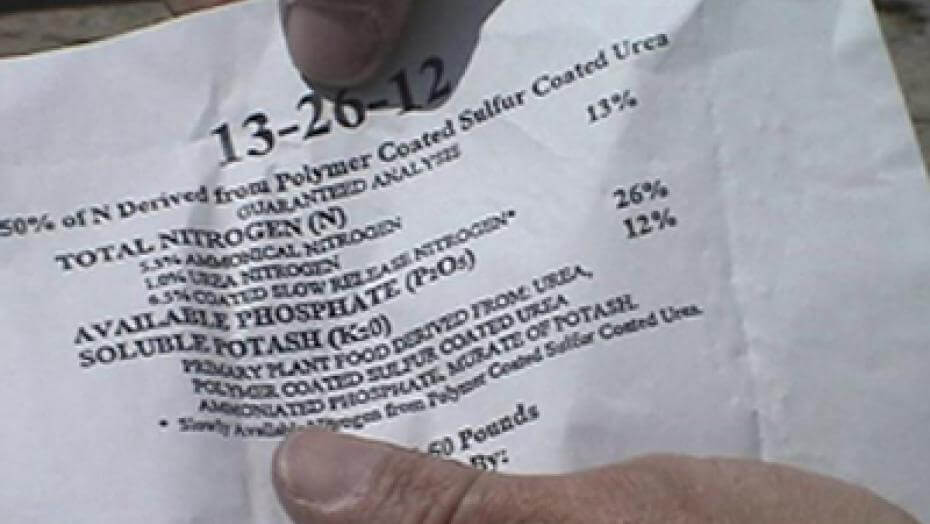 A man holding a paper tag of fertilizer components